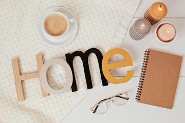 Word home , candles, coffee and white plaid. Comfort and cozy slow life concept. Flat lay, top view