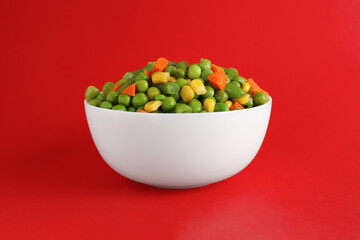 Mix of fresh vegetables in bowl on red background