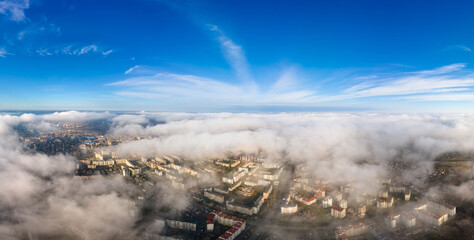 Top aerial view of fluffy white clouds over modern city with high rise buildings