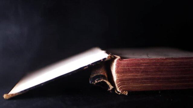 Old worn open book on dark smoke background