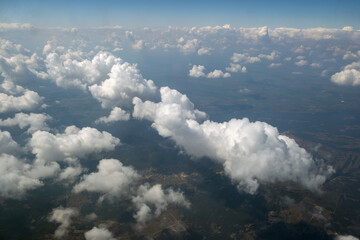 Aerial view from airplane window of white puffy clouds on bright sunny day