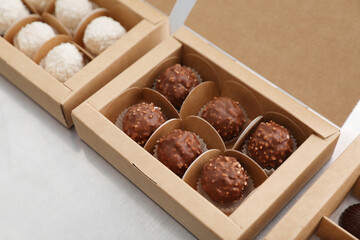 Different delicious chocolate candies and boxes on white table, closeup. Production line