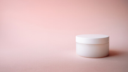 a white jar of cream without a label on a pink background, copy space