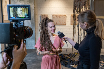 Young artist giving an interview to reporter in honor of the opening of a new art gallery