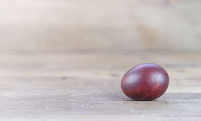 Naklejka na ściany i meble One painted burgundy egg is lying on the table