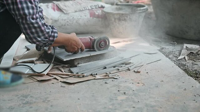 Construction worker using electric grinder cutting on ceramic tile