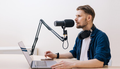 Man recording podcast in white studio. hand holding mobile phone in audio home studio. Male with...