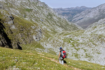 Fototapeta na wymiar woman with backpack descending through a valley between mountains