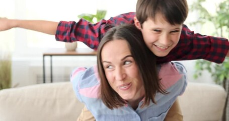 Happy mother piggybacking her son at home