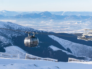 gondola ski lift in mountain ski resort, winter day, snowy spruce forest