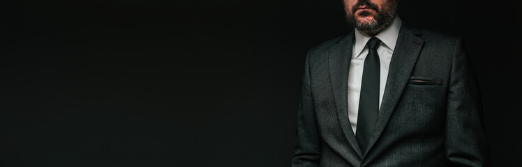 Panoramic low key portrait of handsome confident businessman in elegant grey suit