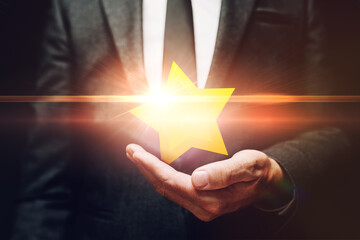 Businessman holding shiny star award in hand