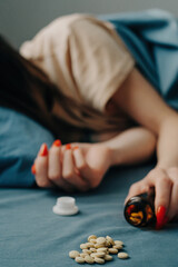 Medicines are scattered on the bed in front of the unrecognizable woman.