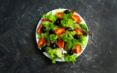 lettuce leaves, tomato, olives in a plate close-up