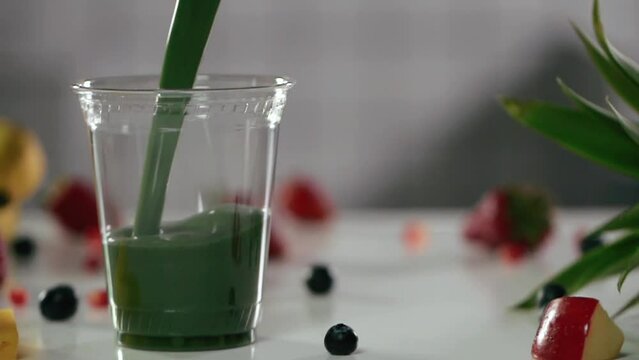 Green drink or smoothie is poured into a glass in the general plan. pack-shot in slow motion
