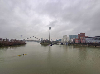 Fototapeta na wymiar View of the Rhein river at a grey winter in Dusseldorf with the Rheinturm television tv tower and bridge,Germany, Europe.