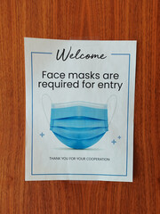 Face masks required sign and symbol on office door entrance.