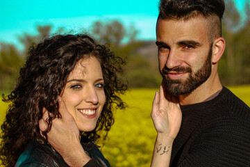 close-up of a couple holding each other's faces and looking at the camera in a field of flowers in springtime