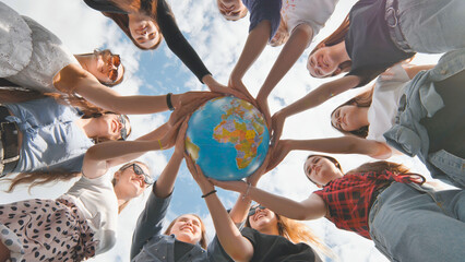 Earth conservation concept. 11 girls hug the earth globe with their hands.