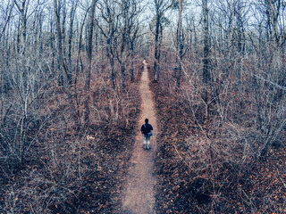 Photo of a man in the center of a path seen from above - aerial view from a drone - road with strong perspective - moody color