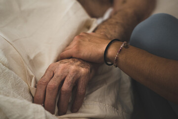 Elderly man having hand held by a loved one.