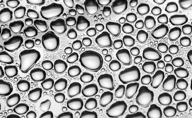 Close up shot of water droplets on metal plate in monochrome