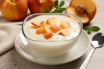 Delicious yogurt with fresh peach on light wooden table