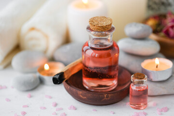 Concept of spa treatment in salon. Natural organic oil, towel, candles as decor. Atmosphere of relax, serenity and pleasure. Anti-stress and detox procedure. Luxury lifestyle. White wooden background