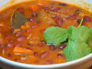 A bowl of bean soup. First course.  Tomato soup with beans, carrots, parsley and bay leaf. homemade food