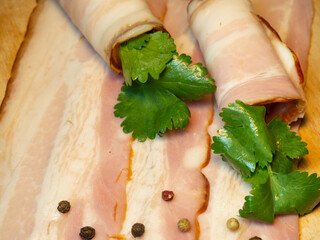 Curvy cut folded into rolls. Pork on a kitchen board with parsley.  Pork belly appetizer.
