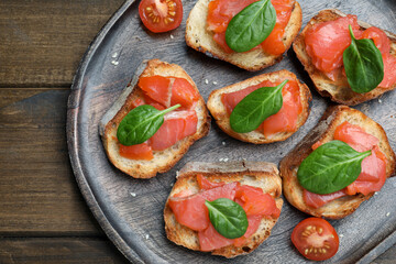 Delicious sandwiches with salmon and spinach on wooden table, top view