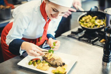 Chef cook in a fancy restaurant kitchen finishing a dish with care and diligence