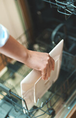Woman loads dishes into the dishwasher.