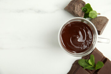 Glass cup of delicious hot chocolate, chunks and fresh mint on white marble table, flat lay. Space for text