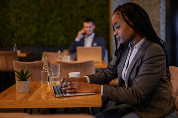 African american businesswoman working on her laptop while drinking coffee in a cafe