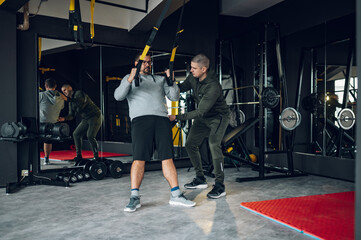 Middle aged men with fitness trainer exercising at the gym