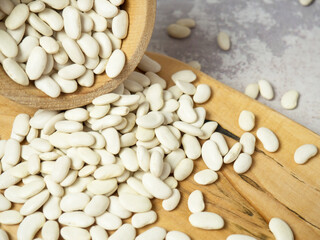 white beans in a wooden cup and spoon are scattered on the table