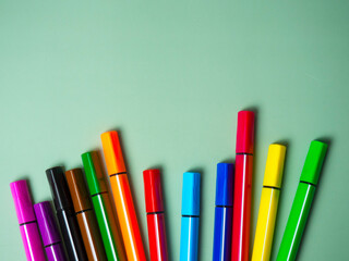 A set of multicolor felt-tip pens, multi-colored felt-tip pens on a green background with space for text