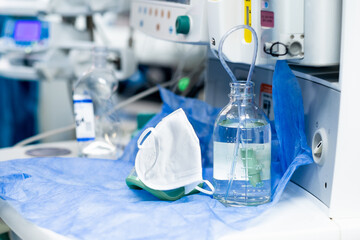 White medical mask and a bottle of saline on the background of modern medical equipment. Selective focus. Hospital background.