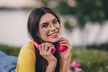 Portrait of gorgeous peaceful person arms touch earphones toothy smile look camera spend free time outside