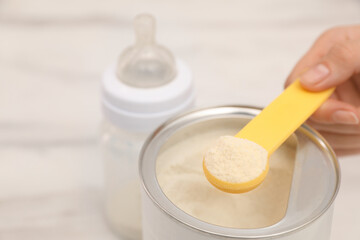 Woman with powdered infant formula at table, closeup and space for text. Preparing baby milk