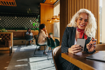 Beautiful woman relaxing in a coffee shop and using phone