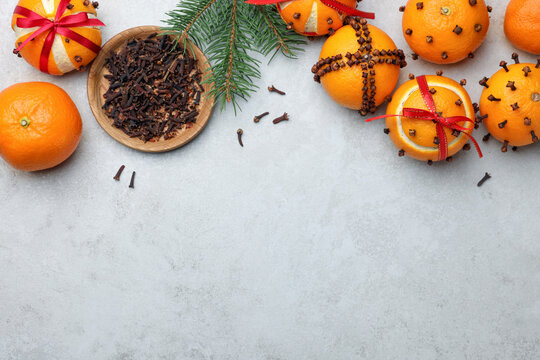 Pomander balls made of tangerines with cloves and fir branch on grey table, flat lay. Space for text