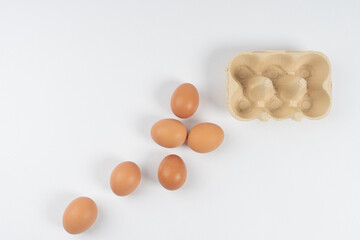 chicken brown eggs lie and next to a box for transportation, on a white background There is a place for text.