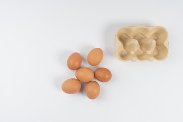 chicken brown eggs lie and next to a box for transportation, on a white background There is a place for text.