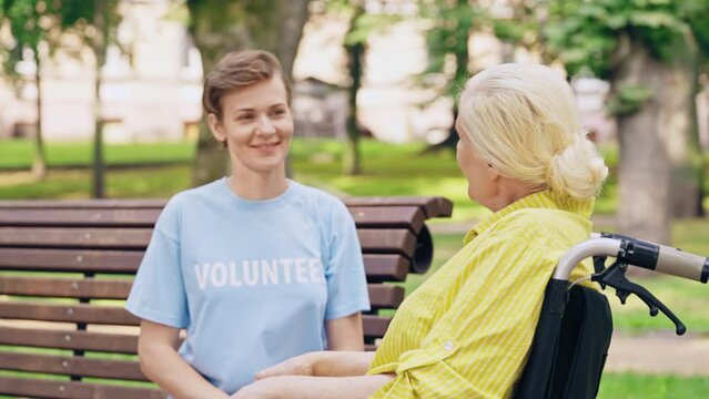 Friendly volunteer talking to senior lady in wheelchair, social care and support