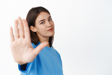 Stop. Smiling young confident girl extending hand, prohibit smth, showing block, rejection gesture,...