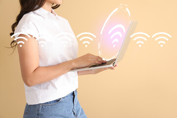 Young woman with laptop using wi-fi on color background