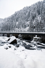Stone bridge over River Grønsdalslona near Latefossen Waterfall during cold winter in Odda, Norway