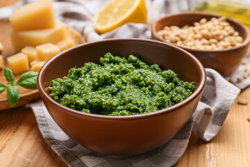 Bowl of tasty pesto sauce and ingredients on wooden background